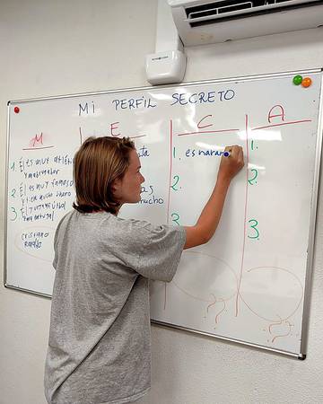 A student writing on the whiteboard in Spanish class